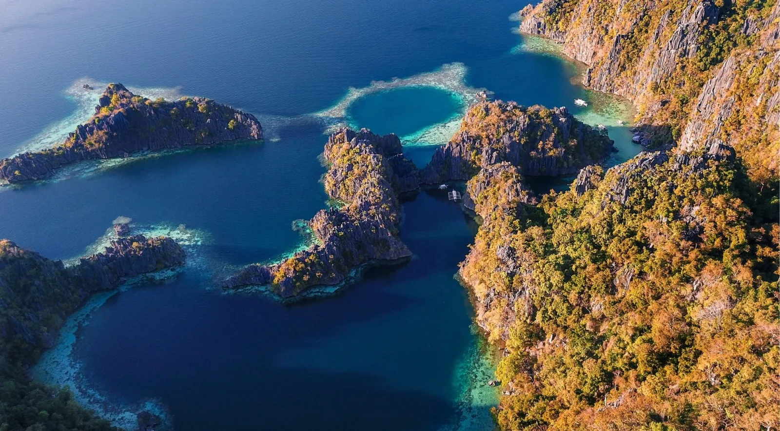 Top-down aerial of Coron's twin lagoons and limestone formations with turquoise and deep blue water